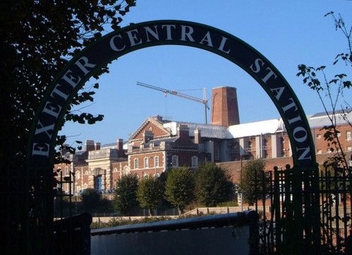 A leafy view of HMP Exeter from Exeter Central Station with blue sky background