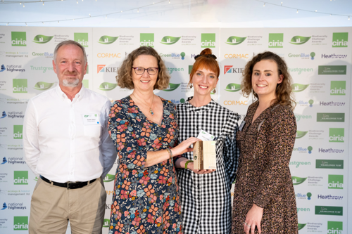 Four Cormac employees proudly hold award while smiling for the camera